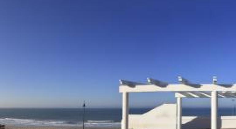 Vista de la playa desde un parador blanco de madera