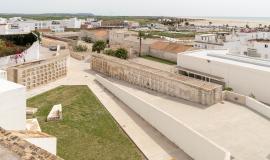 Se aprecia una vista aérea del cementerio en primera posición, el patio de la chanca en el medio de la imagen y al fondo el mar de Conil en un día soleado