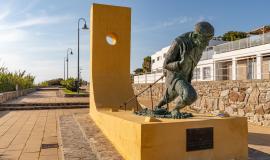 Se aprecia una estatua de un pescador tirando de las redes de pesca en una avenida en un día soleado