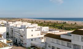 Se ven casas blancas desde una vista aérea y al fondo el mar azul en un día soleado